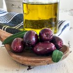 Kalamata Oliven auf Kochlöffel und Olivenöl Karaffe